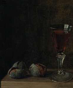 Ett glas vin med valnötter på ett bord