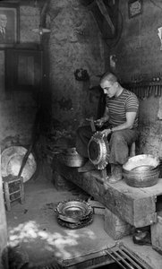 Italiensk metallarbetare hamrar på en plåtform för att tillverka ett upphöjt kärl eller en kruka, Italien