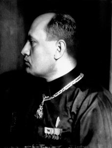 Halvlångt porträtt i profil av Benito Mussolini i svart skjorta och militärdekorationer (s/v foto)