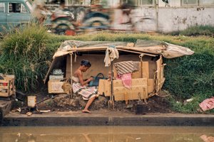Kartonghydda som fungerar som hem längs en avloppskanal. Jakarta, Indonesien.
