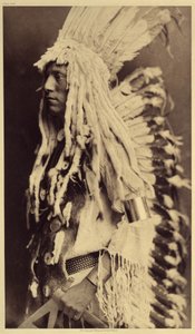 Gammal person, Piegan. Unga män missar inte något tillfälle av offentliga festligheter för att ta på sig kläderna till sin krigarfar. Foto taget från volym 6 av uppslagsverket publicerat av Edward S. Curtis (1868-1952) om indianerna i Nordamerika, med en f av Edward Sheriff Curtis