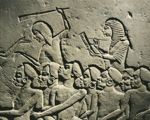 En grupp negroida fångar omringade av vakter beväpnade med klubbor medan en skriftlärd skriver en rapport. Relief från Horemhebs grav i Saqqara, detalj av Egyptian 18th Dynasty
