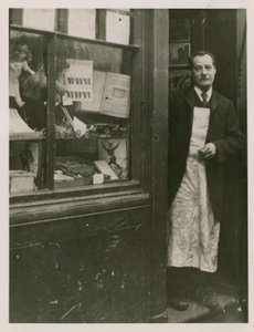 En butiksinnehavare som står i dörröppningen till sin butik av English Photographer