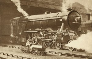 Pojke kör ett leksaksånglok framför ett riktigt ånglok (svartvitt foto) av English Photographer