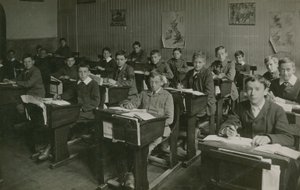 Manliga elever som sitter bakom sina skrivbord under en lektion i skolan av English Photographer