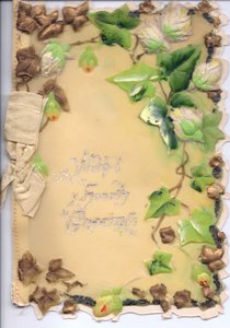 Ett gratulationskort av plast med guld och grön präglad murgröna och en beige rosett, cirka 1910 av English School