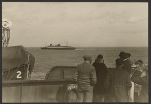 [Grupp av människor på ett fartygsdäck som ser ett annat fartyg segla förbi i fjärran] av Erich Salomon