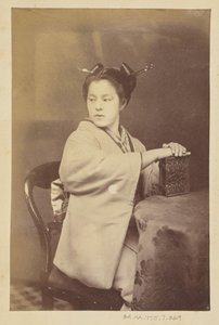 [Sittande japansk kvinna med ett album med cartes-de-visite vid ett bord] av Felice Beato