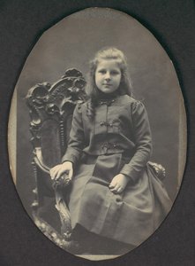 [Flicka med ringlar, sittande, trekvartslängd], 1890-tal.