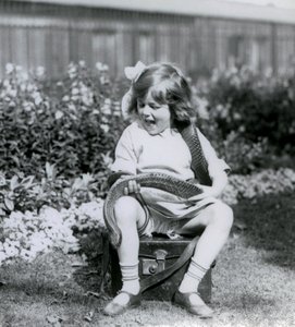 En ung flicka Betty som håller en östlig indigorm när hon sitter på en läderkoffert, London Zoo, 1924 av Frederick William Bond