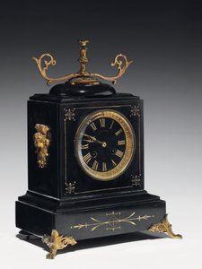 En mantelklocka av svart kompositionssten, med inskuren dekor, med ben, slutstycken och beslag i förgylld mässing, av Jausions av Pau, Frankrike, ca 1876-78 (svart kompositionssten, med inskurna dekorationer av French School