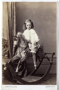 Ung flicka sitter på en gunghäst, 1860-tal (albumintryck)