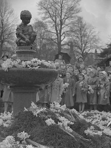Barn placerar klasar av påskliljor på fontän med staty på toppen av Joseph Hardman