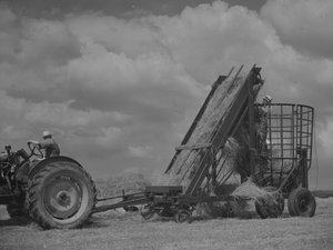 Traktor drar mobil ram och hö lastas in i den av Joseph Hardman