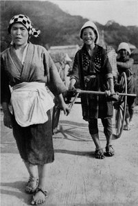 Tre generationer av kvinnor som flyttar en vagn med mormor bak, knuffande, c1900, 1921.