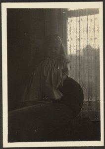 [Liten flicka lutar sig mot stolsrygg] av Louis Fleckenstein