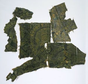 Fragment av en kaftan täckt med ett sidentyg med ett Senmurv-mönster. Moshchevaya Balka begravning M av Medieval Culture of the North Caucasian