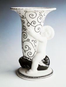 Vas med svart dekor, konformad kropp som hålls av en kerub, Vereinigte Wiener Und Gmundner Keramik, Österrike, 1900-tal (vitt emaljerat lergods) av Michael Powolny