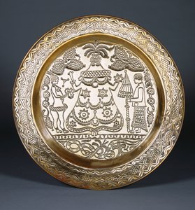 En Efik mässingsladdare präglad med en central klädd kvinnofigur och två tjänare som håller i en fläkt och ett paraply