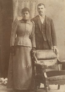 Fotografi av ett afroamerikanskt par som står bakom en stol, ca. 1890. av Schmitz Studio