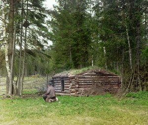 En man framför en hydda för vedhuggare och kuria (kolbränning) i skogen, ryska imperiet, mellan 1905 och 1915