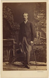 [Oidentifierad man med mustasch, som håller en hög hatt och ett paraply, stående] av Southwell Brothers