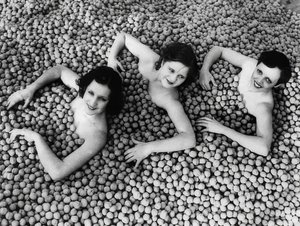 Tre unga kvinnor badar i ett hav av valnötter. Amerika. 1932 av Unbekannt