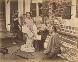 [Japansk kvinna i traditionell klänning poserar med två män], 1870-talet. av Unbekannt