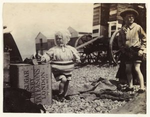 Två barn vid badmaskiner, c 1895, En ögonblicksbild av två barn vid havet, stående bland en grupp badmaskiner på stranden av Unbekannt