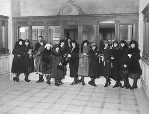 USA: c.1926 En grupp kvinnor som står vid kassans fönster för "Spara" på en bank. (s/v bild) av Unbekannt