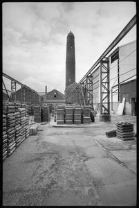 En allmän bild av Elswick Shot Tower, revet 1968-69, som användes för att skapa blyhagel, med en gård med paletter i förgrunden, ca 1955-69 (s/v foto) av Unbekannter Künstler