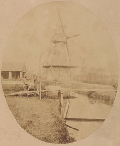[Målare i hatt vid staffli som målar en väderkvarn] av Unknown artist