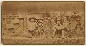 [Två pojkar sitter på marken med en hund] av Unknown artist