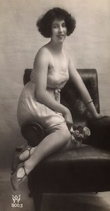 En ung kvinna poserar i sin underkjol, sittande i en fåtölj av Unknown photographer
