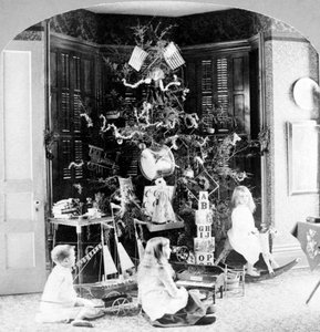 Barn samlades vid foten av trädet omgivna av presenter på julmorgonen. av Unknown photographer