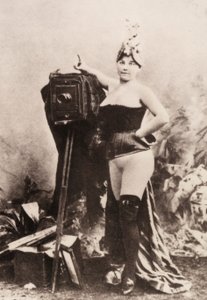 Porträtt av en delvis naken kvinna som lutar sig mot en antik kamera. av Unknown photographer