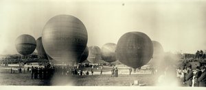 Hot air balloons at a field in South St. Louis ready for launch; one is already in the sky in the distance av W.C. Persons