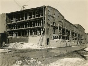 Byggarbetsplats, två män står på den öppna sidan av en lagerbyggnad; Robbins und Ripley Engineers and Contractors, 23 mars 1916 av William Davis Hassler