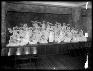 En grupp små flickor poserade på en liten scen med fans, förmodligen det romersk-katolska föräldrahemmet, Kingsbridge, Bronx, ca 1911 av William Davis Hassler