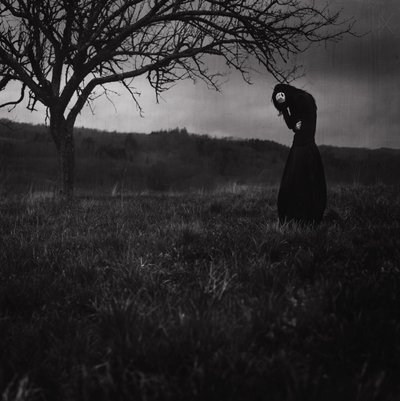 Sorgsen figur i mörkt landskap av Anja Matko