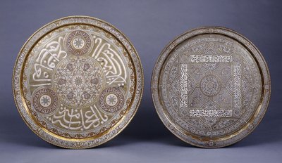 Två cirkulära brickor i guld, koppar och silver inlagda i mässing, dekorerade med arabesker och inskriptioner, sent 1800-tal av Arabic School