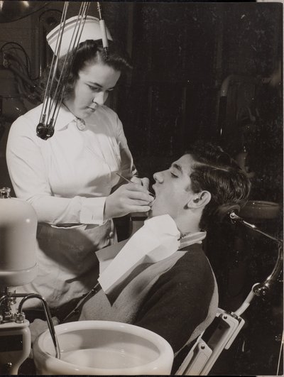 [Tandhygienist inspekterar en patients mun] av Arnold Eagle