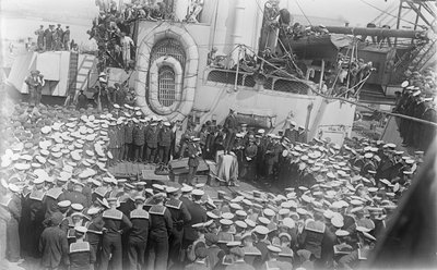 Sjömän trängs runt Australiens premiärminister The Hon William Morris (Billy) Hughes när han tilltalar dem på däcket av HMAS Australia vid varvet i Devon, England, 21 maj 1916 av Australian Photographer