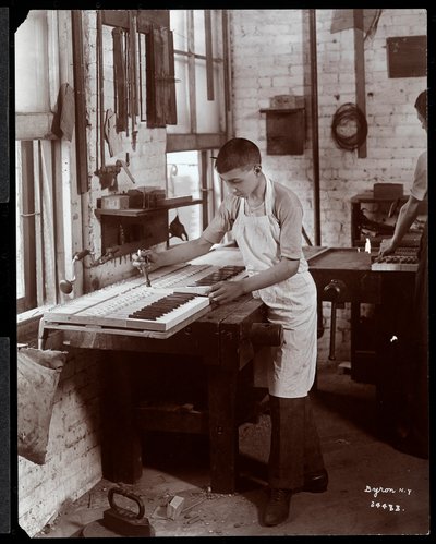 En ung man som arbetar i Harrington Piano Co.-fabriken, 1907 (silvergelatintryck) av Byron Company