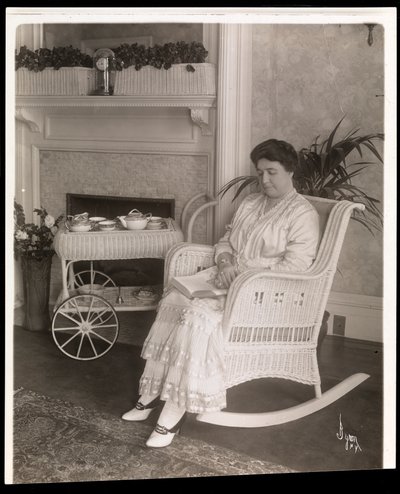 Mrs. Howard satt med en bok i en gungstol i sitt hem på 200, 5th Avenue, New York, 1915-6 (silvergelatintryck) av Byron Company