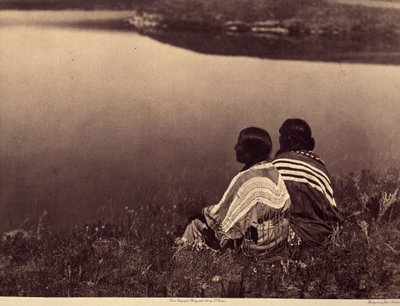 En ledig timme - ett ögonblick av lugn: Piegan indianer som sitter på kanten av en vattenmassa. Foto taget från volym 6 i Encyclopedia publicerad av Edward S. Curtis (1868-1952) på indianerna i Nordamerika, med ett förord av Theodore Roosevelt. B av Edward Sheriff Curtis