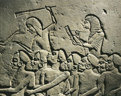 En grupp negroida fångar omringade av vakter beväpnade med klubbor medan en skriftlärd skriver en rapport. Relief från Horemhebs grav i Saqqara, detalj av Egyptian 18th Dynasty