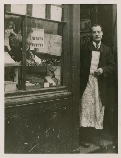 En butiksinnehavare som står i dörröppningen till sin butik av English Photographer