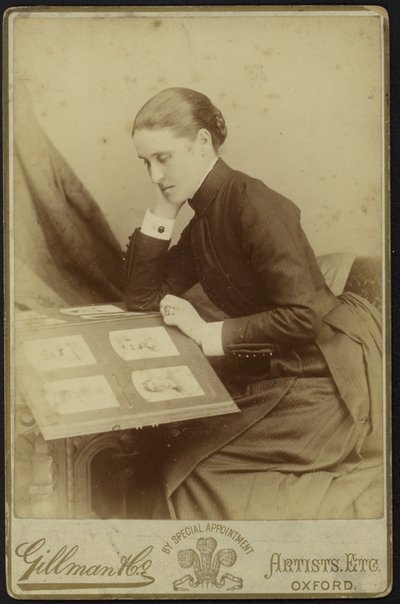 Figur av en kvinna som sitter och inspekterar ett fotoalbum av English Photographer