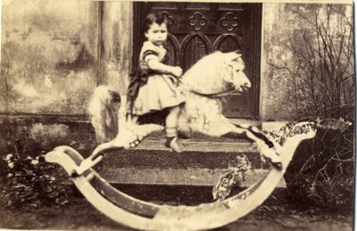 Liten flicka på en stor gunghäst i en trädgård, 1860-tal (albumintryck) av English Photographer